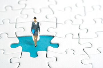 Miniature people toy figure photography. A businesswoman standing above missing piece of puzzle...