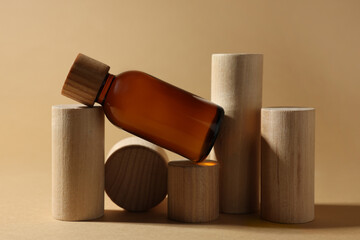 Composition with glass bottle of cosmetic product on dark beige background