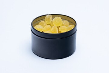 Yellow sugary gummies inside a black can.
