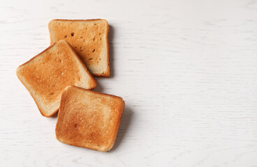 Slices of delicious toasted bread on white wooden table, top view. Space for text