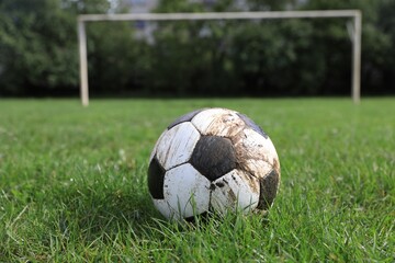 Dirty soccer ball on green grass outdoors