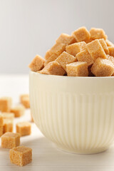 Brown sugar cubes on white table, closeup