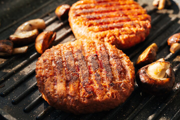 Pilz burger patties sizzling on a hot barbecue pan with mushrooms. Vegan food. Close up