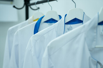 A set of hanging medical gowns. White medical gowns on a hanger close-up.