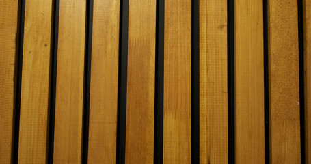 Lacquered wooden slats. Black wall with decor. Surface, abstraction, room interior.