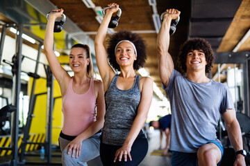 Group of fit people lifting dumbbells during an exercise class at the gym