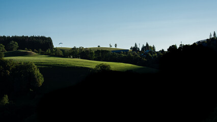 A sunset view of a countryside with a paraglider
