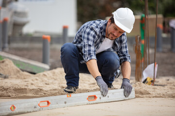 bearded worker working with spirit level at construction site