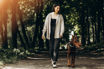 Obraz premium Woman with her dog doberman having fun in park
