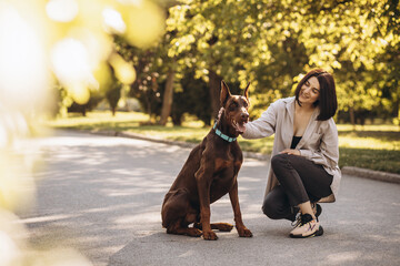 Woman with her dog doberman having fun in park