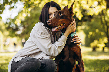 Woman with her dog doberman having fun in park