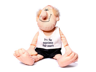 Soft toy, an old man in a T-shirt and shorts sits isolated on a white background.