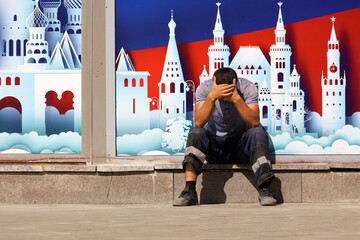 Man worker in uniform sitting on city street on background of decoration with Moscow landscape....