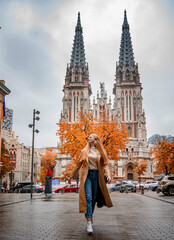 blonde woman in beige coat walking on the street in the Kyiv city in autumn park