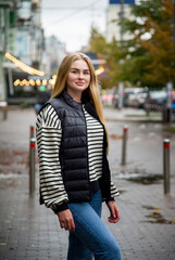 smiling woman with long blond hair in jeans walking on the street