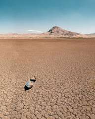 Abandoned row boat on cracked soil on lake bed dried up due to global warming and drought