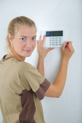 female contractor fitting electronic keypad to wall