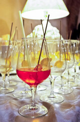 set of glasses with spritz for a party or wedding, with white lamp in the background