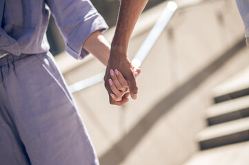 Close up picture of a couple walking hand in hand
