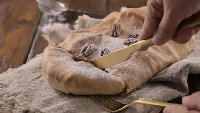 Strudel with apple. A typical sweet pastry in northern Italy, in Trento. Pie twisted with apple, cinnamon, nuts, in puff pastry, sprinkled with powdered sugar. 4k footage
