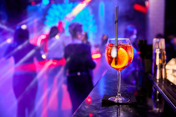 Alcoholic cocktail in a nightclub against the backdrop of dancing people