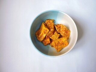 Fried tofu and tempeh in a bowl with white background