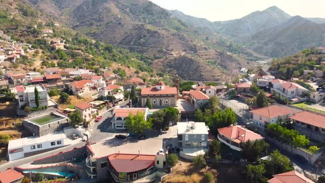 Aerial drone footage of traditional countryside hilltop village Farmakas, Nicosia, Cyprus. Establish scene of christian church Saint Irene, ceramic tiled roof volcanic rock architecture from above.