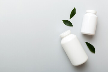 supplement pills with medicine bottle health care and medical top view. Vitamin tablets. Top view mockup bottle for pills and vitamins with green leaves, natural organic bio supplement, copy space