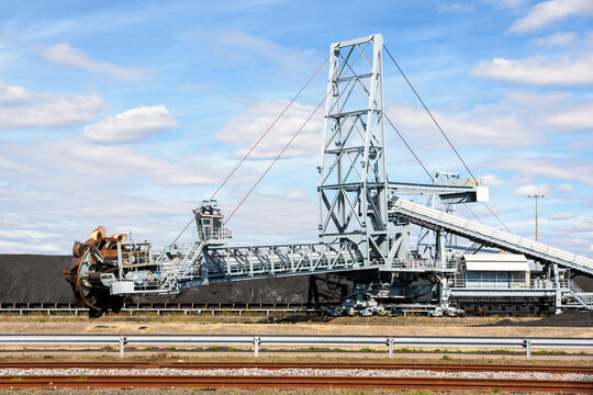 A bucket-wheel stacker-reclaimer and a coal stockpile in a thermal power station on a sunny summer day.