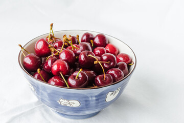 Bowl of fresh red cherries on white background. Sweet cherries in the bowl on white background closeup. Cherry organic berries harvest - healthy eating and food concept