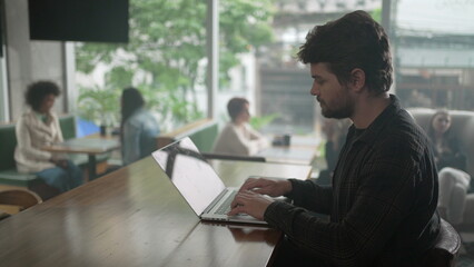 Entrepreneur in front of laptop at coffee shop. Young man freelancer using computer at cafe place