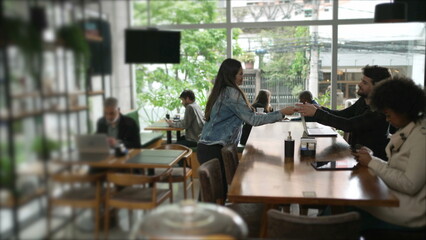 Fototapeta na wymiar Customers inside coffee shop. Female friend bringing espresso to male friend at cafe restaurant place interior