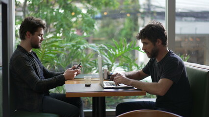 People using technology sitting at coffee shop. Male entrepreneur typing on laptop. colleague using smartphone browsing internet working at cafe place