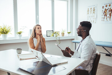 Endocrinologist examining throat of young woman in clinic. Women with thyroid gland test ....