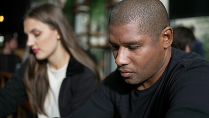 Pensive African American man seated at coffee shop thinking in contemplation. A thoughtful black person
