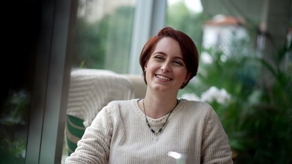 One happy redhair woman smiling and laughing in interaction with other person. Portrait girl sitting at coffee shop