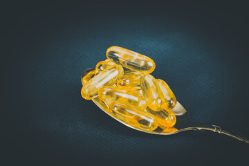 Fish oil in white bowl with golden spoon on black background.