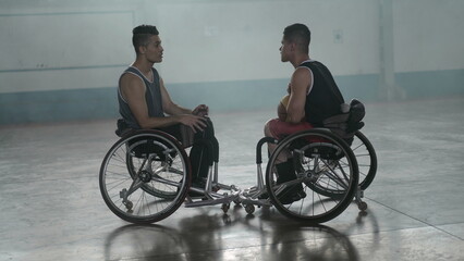 Obraz premium Two disabled athletes in conversation in wheelchairs. Handicapped basketball players wearing sportwear