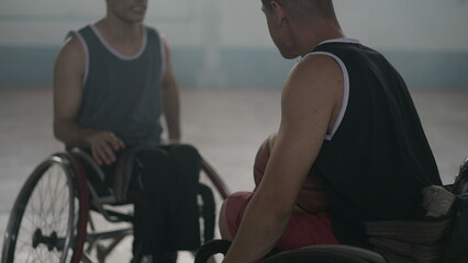 Fototapeta na wymiar Two disabled athletes in conversation in wheelchairs. Handicapped basketball players wearing sportwear