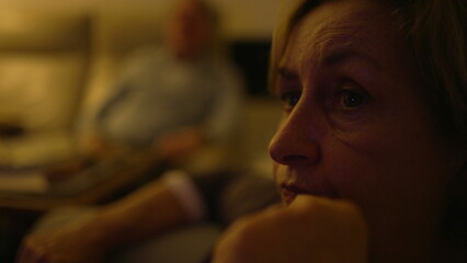 Senior woman closeup face watching television news. Older baby boomer generation eyes staring at TV