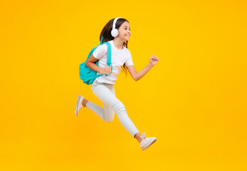 Fototapeta na wymiar Schoolgirl with backpack hold aplle ready to learn. School children with school bag on isolated yellow studio background. Excited teenager, jump and run, jumping child.