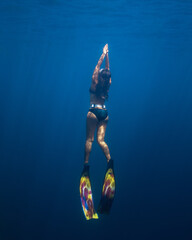 Female freediver fun diving swimming to the surface in the ocean sea holding breath