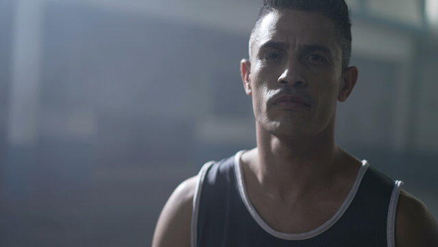 Portrait of a South American hispanic man wearing sportwear looking at camera with dramatic lighting with serious expression