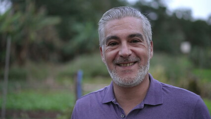 Portrait of a happy senior man smiling at camera in the evening. Older person with gray hair