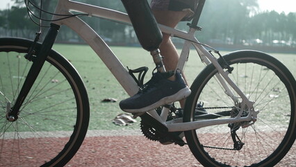Person with prosthetic leg riding bicycle outdoors. A disabled athlete rides bike