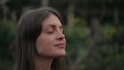 Fototapeta premium Meditative young woman closing eyes in meditation. Contemplative person opening eyes to sky with HOPE
