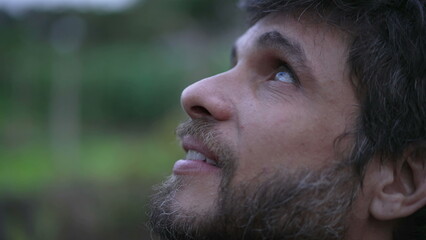 Obraz premium Man looking up at sky smiling having HOPE and FAITH. Person in 30s feeling the presence of GOD feeling FREEDOM