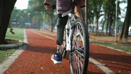 Disabled person riding bicycle using prosthetic leg outdoors