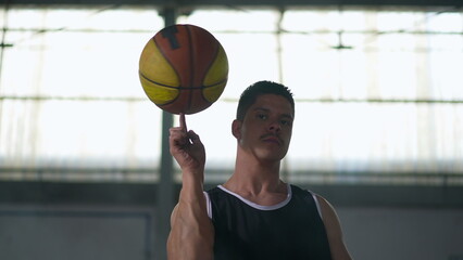 Disabled Athlete spinning basketball ball with finger. Handicapped athlete in wheelchair spins ball...
