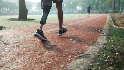 Determined disabled athlete running outside with prosthetic leg. Motivational amputee on runner track